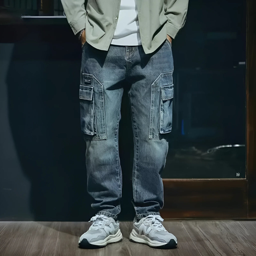 Man wearing blue loose straight-leg denim trousers with a zip fly, showcasing a casual retro style.