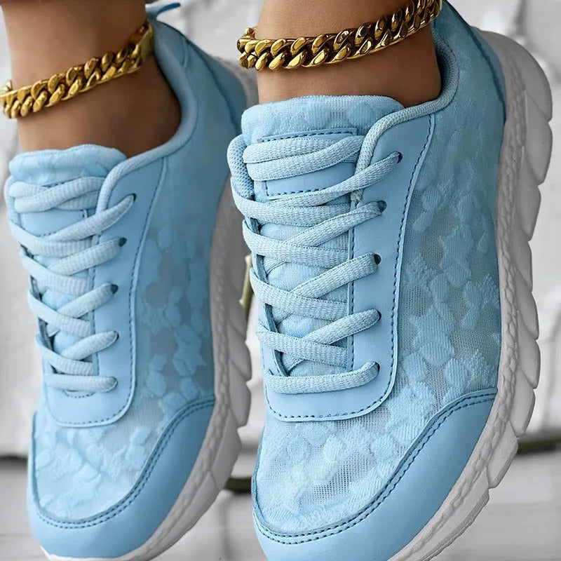 Women's white canvas sports shoes with round toe and flat heel on a neutral background.
