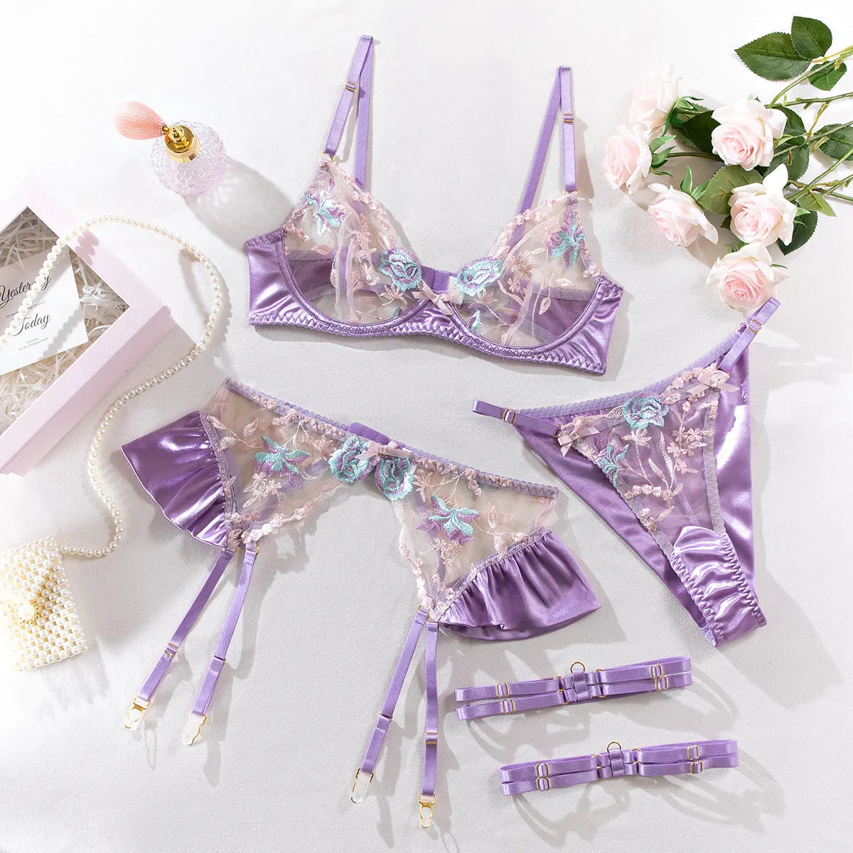 Light purple satin lingerie four-piece set with bra, briefs, garter belt, and suspenders
