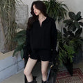 Women's creamy-white knitted shorts suit set with cable pattern, long sleeve top, and elastic waist.