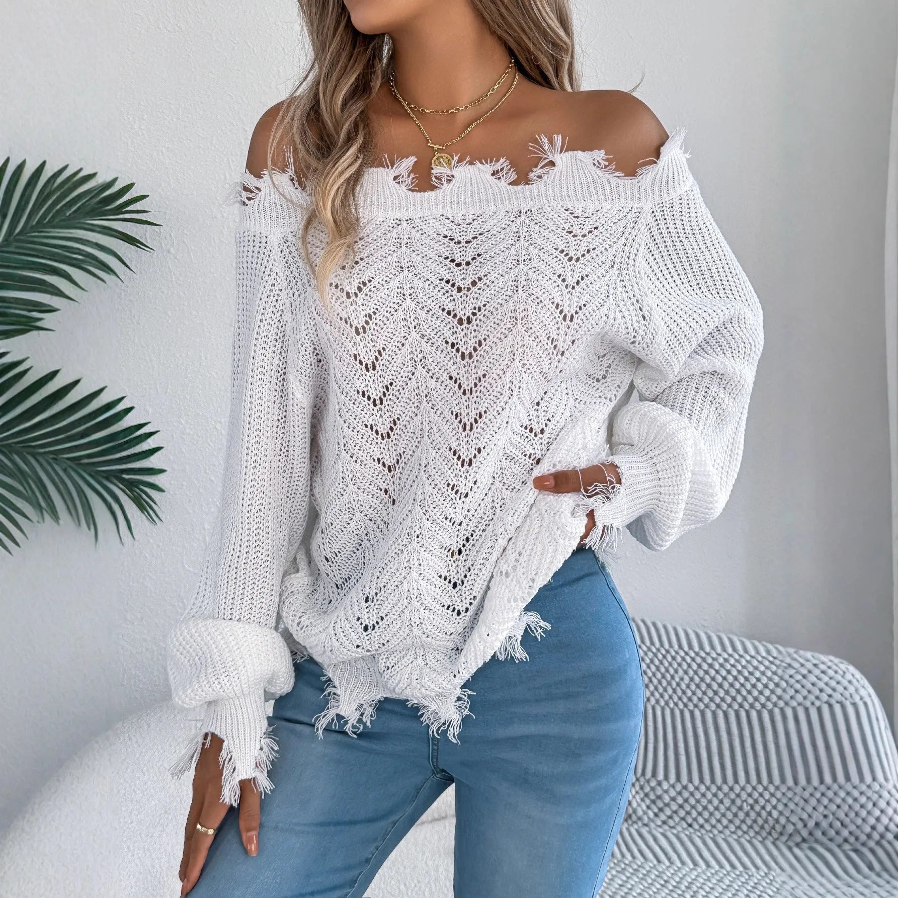 White hollow-out design off-the-shoulder long sleeve acrylic pullover sweater on a hanger.