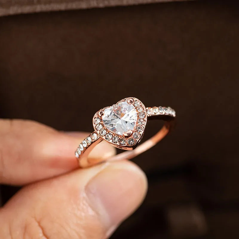 Heart-shaped crystal wedding ring in rose gold or silvery finish on white background