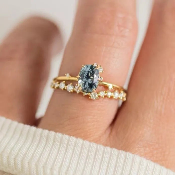 Gold-plated floral fashion ring with a central green zircon stone on a hand.
