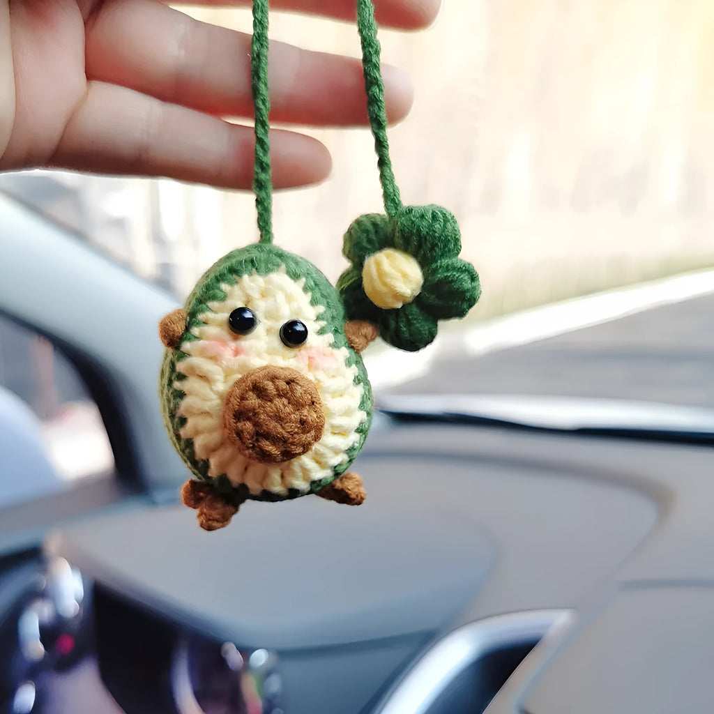Handmade crocheted car pendant in avocado, pink rainbow, and red rainbow cartoon designs.