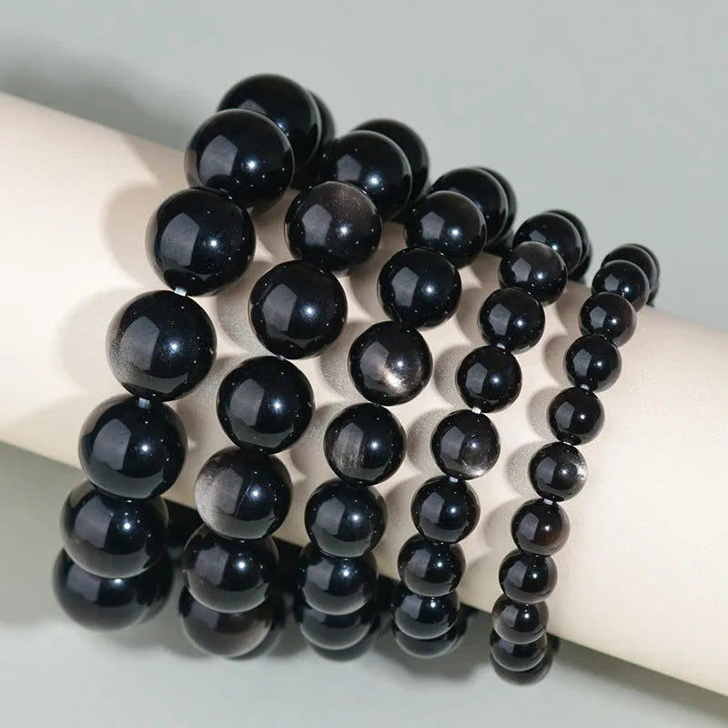 Hand-woven round obsidian bead bracelet for couples, showing colour options on a wrist.