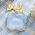 Small dog wearing blue elastic vest with heart texture and decorative bow