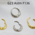 Close-up of a titanium alloy concave-convex nose ring in gold finish, showing detailed carving texture.
