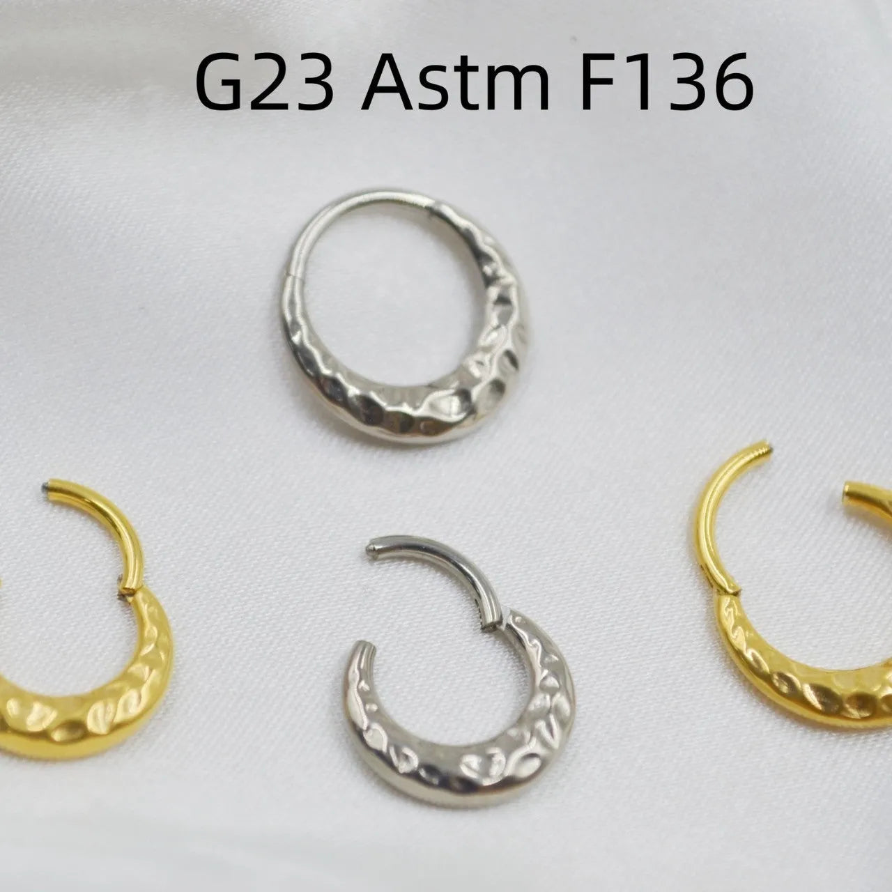Close-up of a titanium alloy concave-convex nose ring in gold finish, showing detailed carving texture.