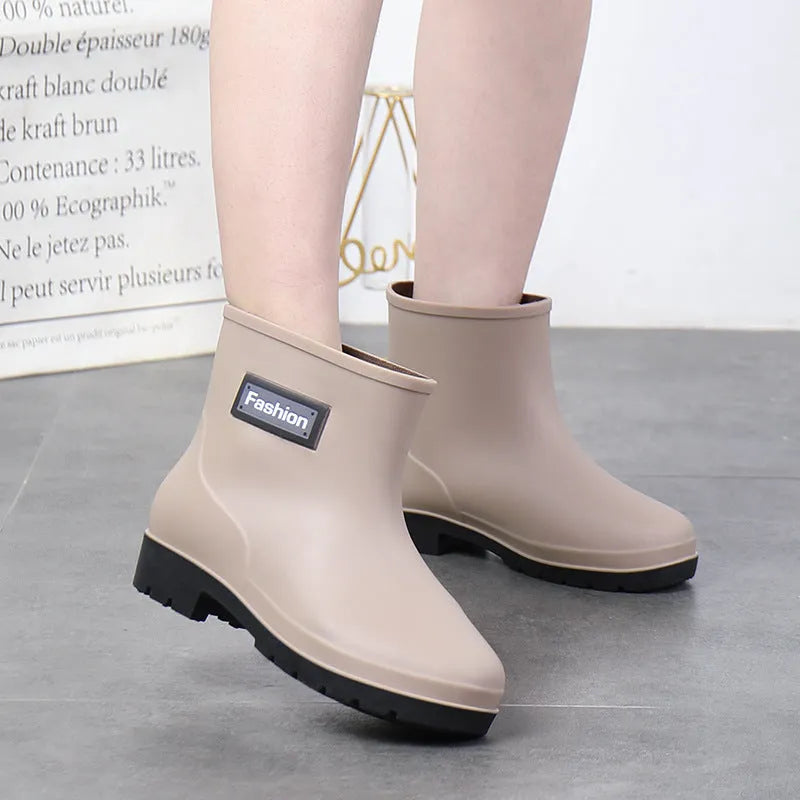 Women's black PVC mid-calf rain boots with a low heel on a wet surface.