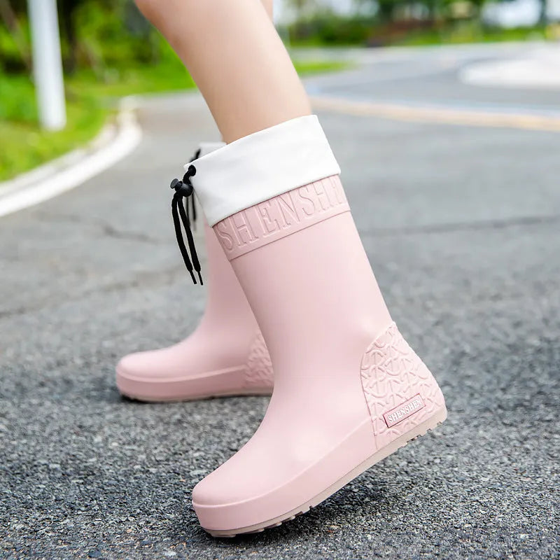 Solid-colour women's PVC rain boot with a non-slip sole in apricot, black, brown, or pink.