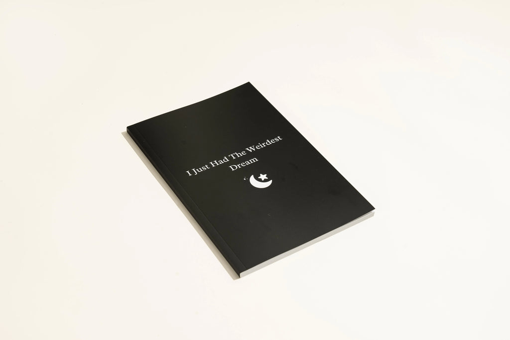 Black hardcover dream journal notebook with minimalist design on a desk.