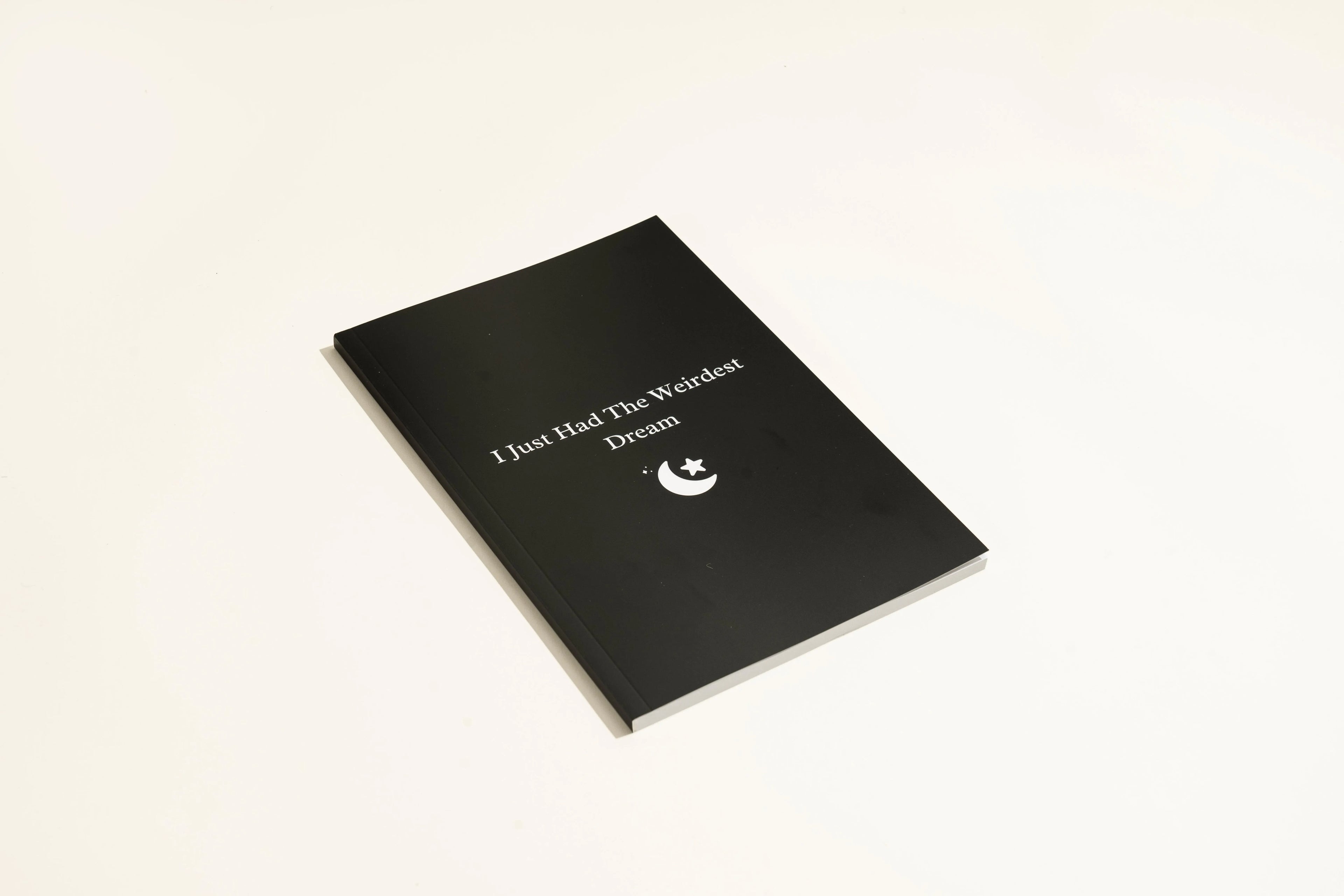 Black hardcover dream journal notebook with minimalist design on a desk.