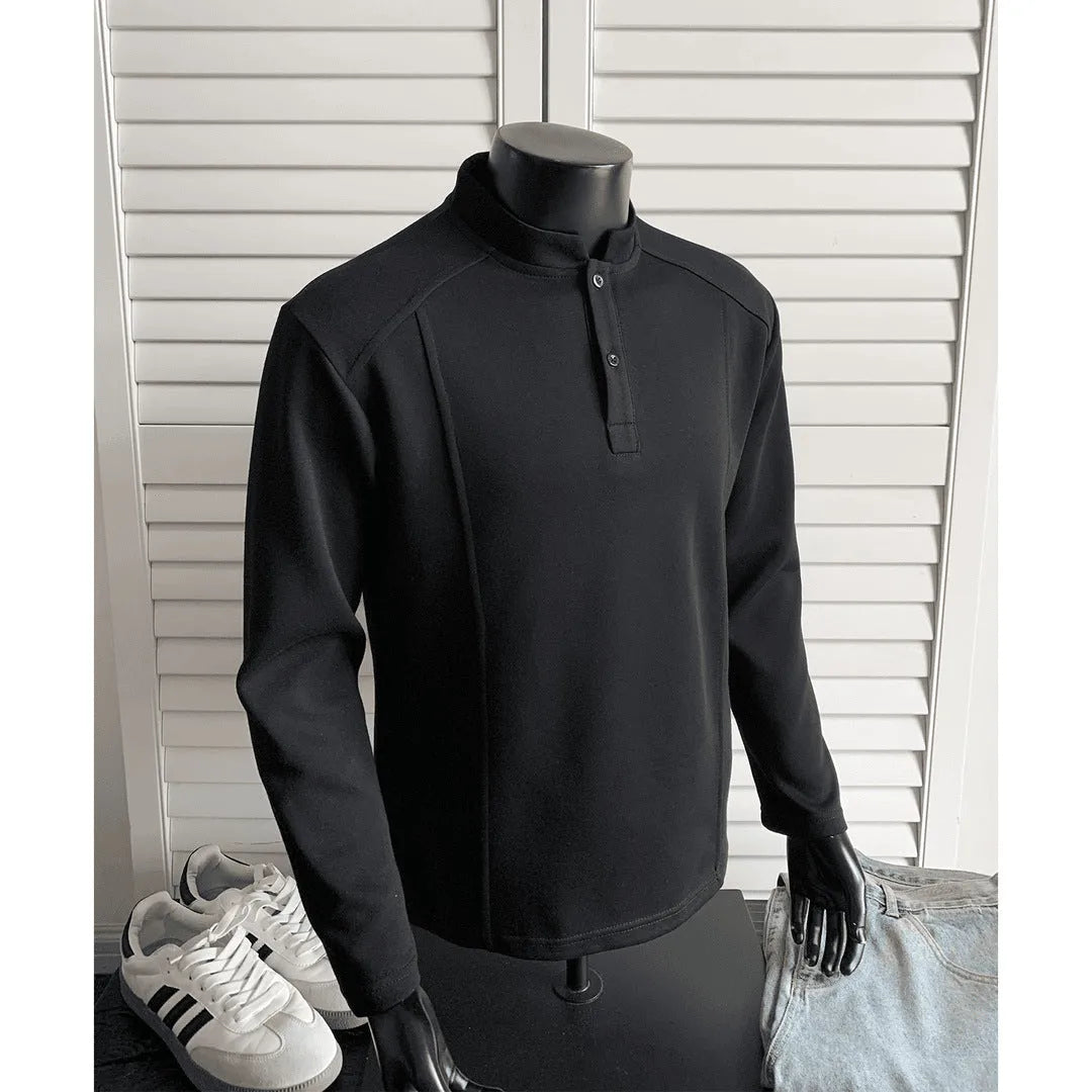 Man wearing a loose fit grey long sleeve sweater with an asymmetric design and a stand-up polo shirt collar.