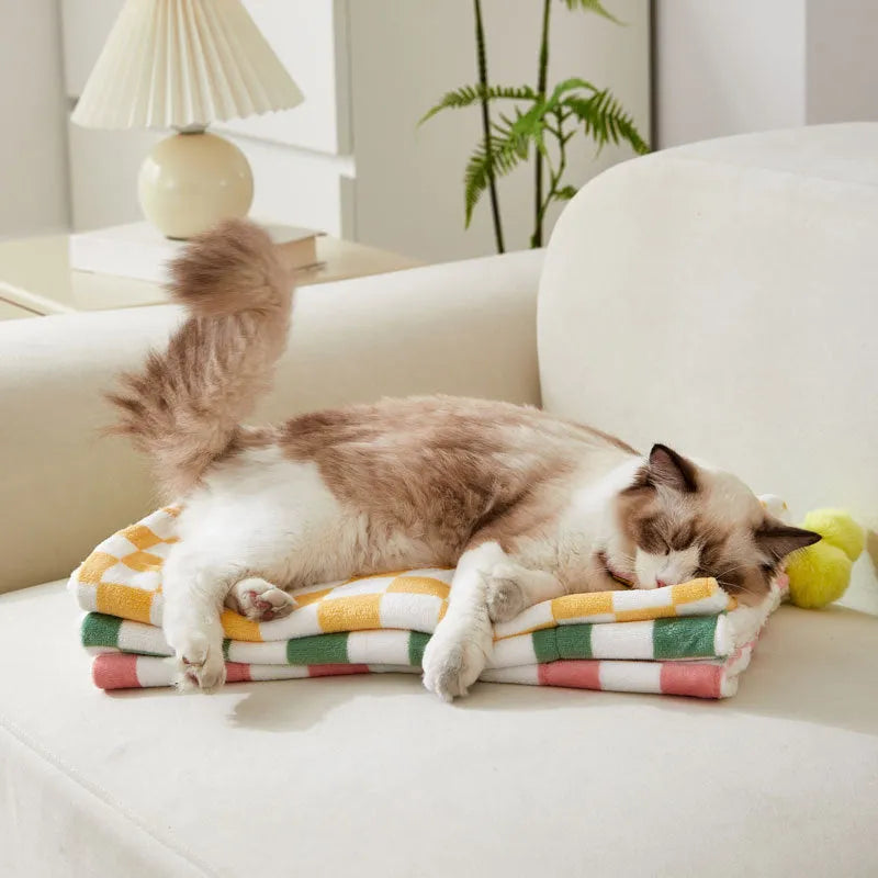 Green plush pet blanket with plaid pattern and fur balls as dog bed mat on sofa