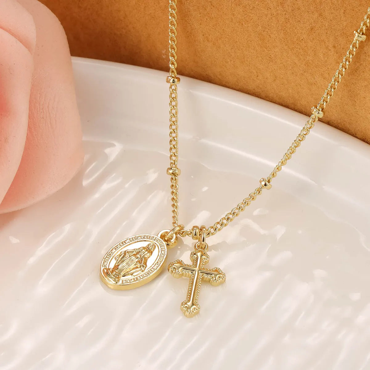 Gold-coloured copper necklace with a geometric cross pendant featuring a Virgin Mary centrepiece.