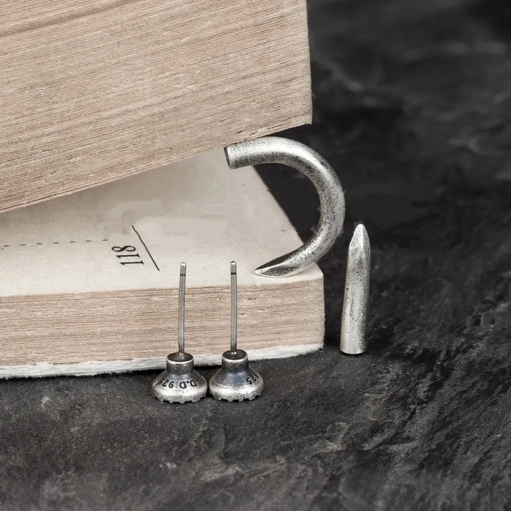 Sterling silver punk-style nail stud earrings on ear hook, showing straight and curved nail designs.