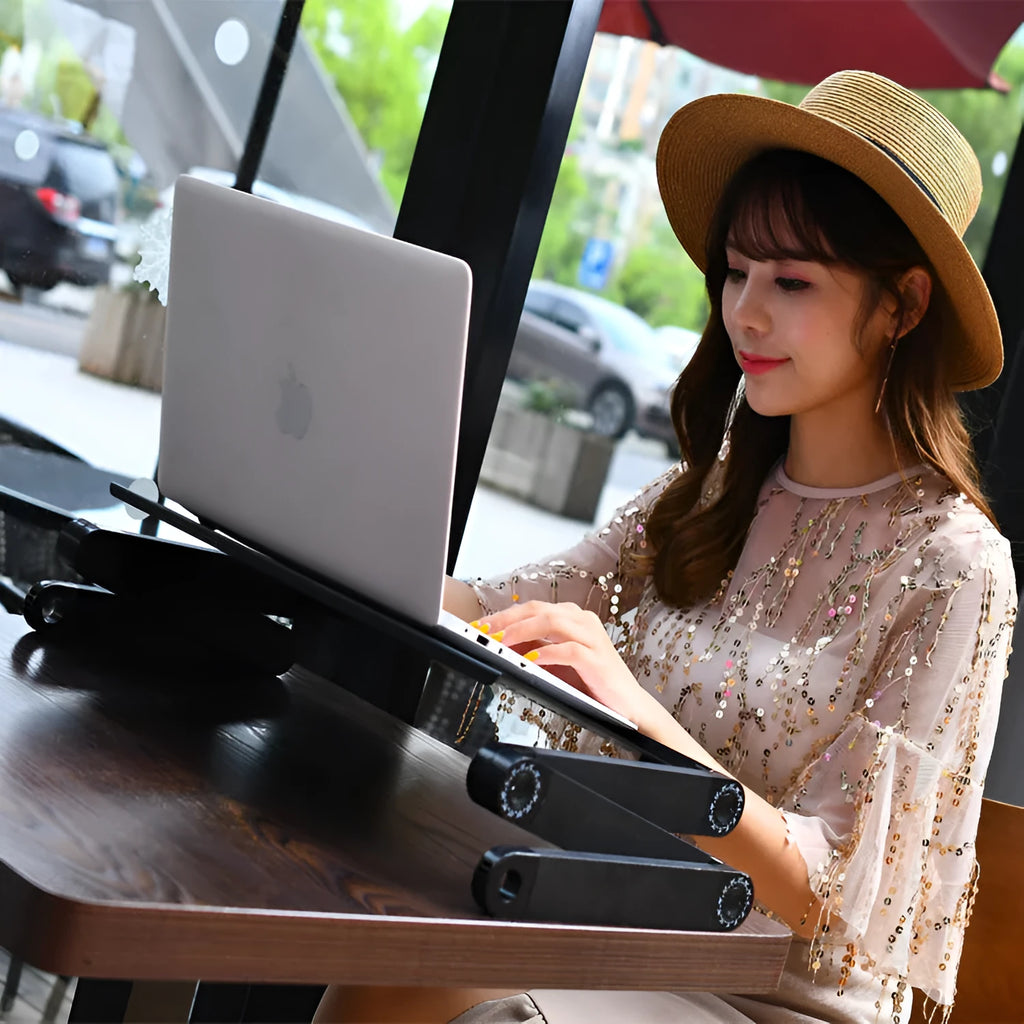 Black folding metal laptop bed desk with cooling fans, shown extended on a bed.