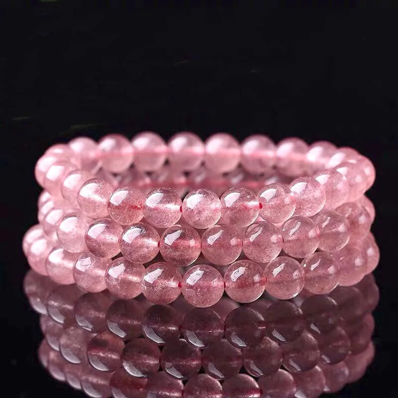 Women's bracelet with polished strawberry quartz crystal beads on an elastic cord, showing 6mm, 8mm and 10mm size options.
