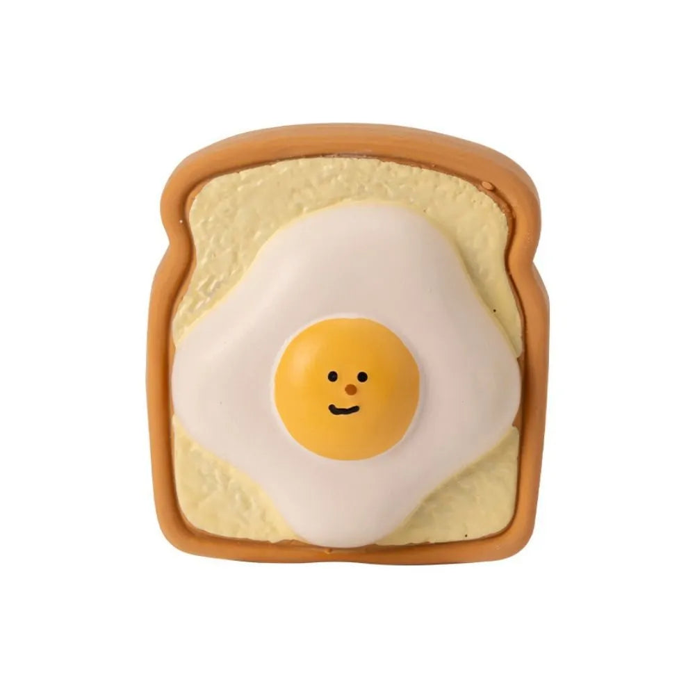 Yellow and green bread-shaped latex dog squeaky toy with cartoon pattern on a white background.