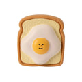 Yellow and green bread-shaped latex dog squeaky toy with cartoon pattern on a white background.