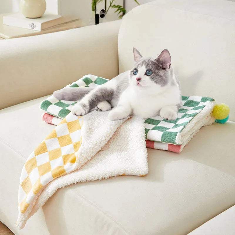 Green plush pet blanket with plaid pattern and fur balls as dog bed mat on sofa