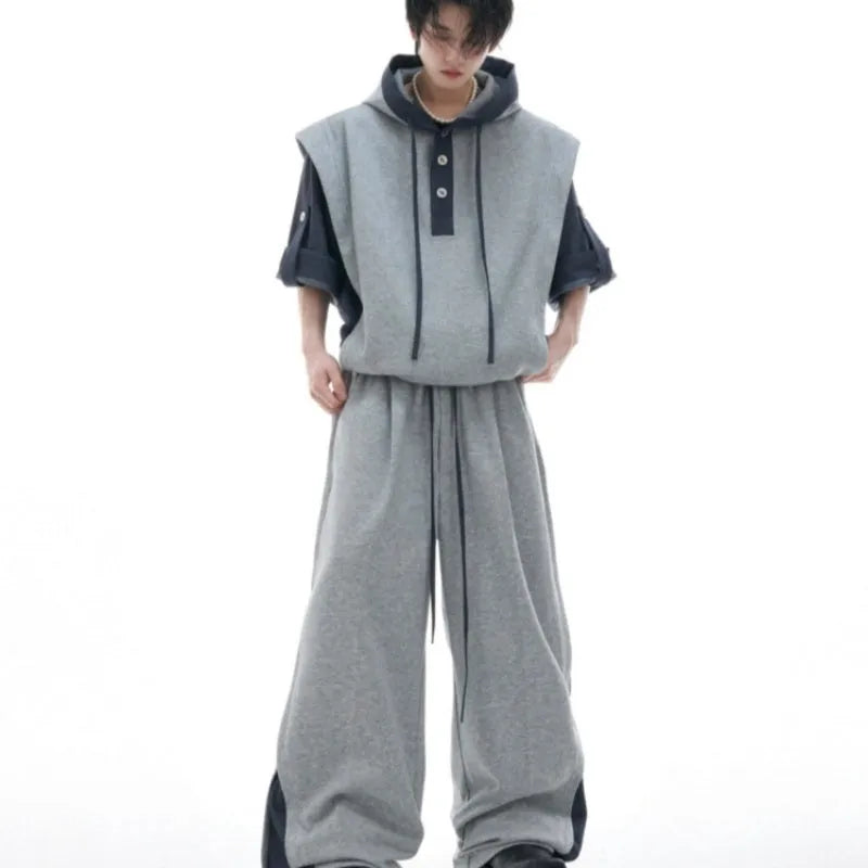 Man wearing a gray hooded short-sleeve sports jacket with 3D stitching and black matching trousers.