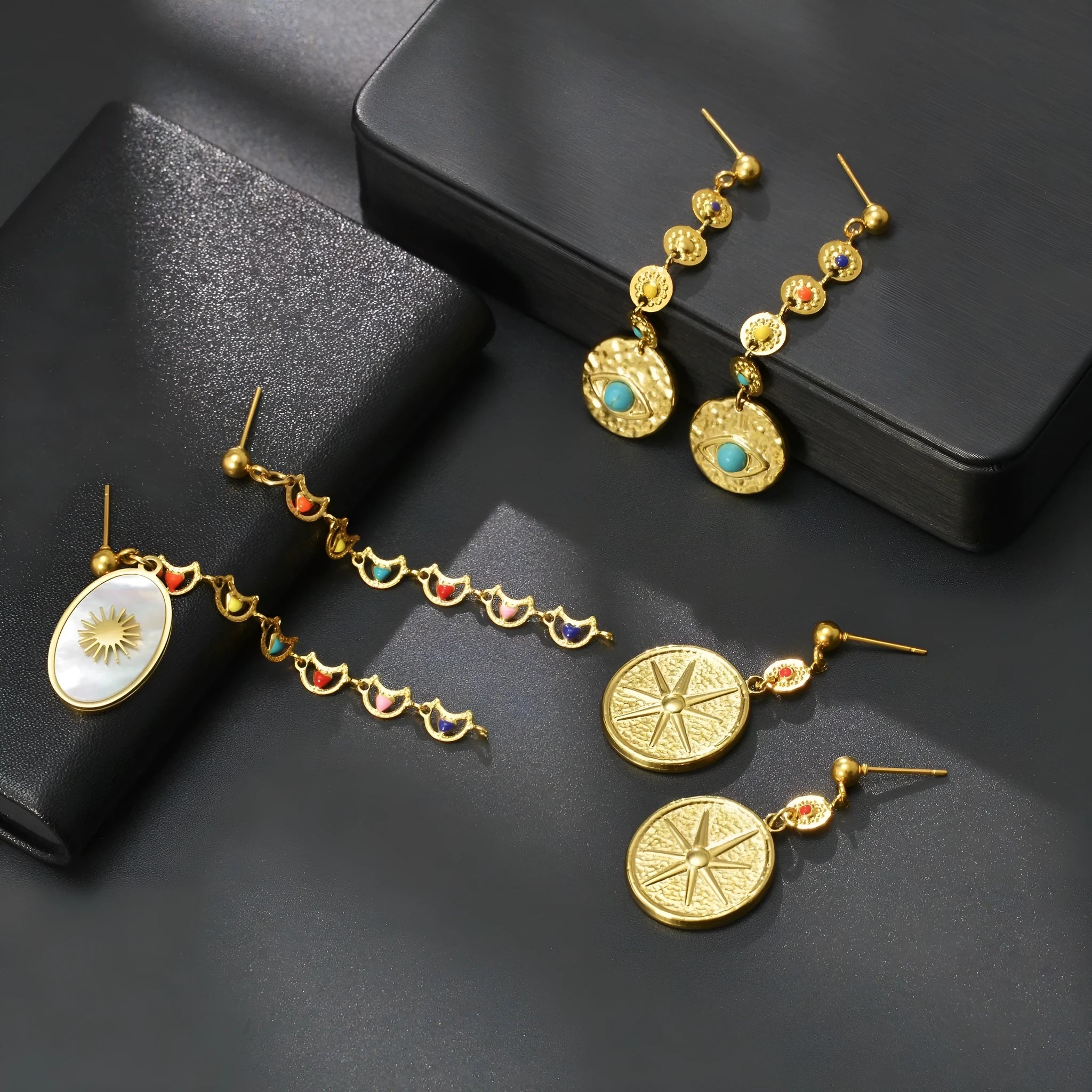 Three pairs of geometric stainless steel earrings showing star, eye and shell sun designs
