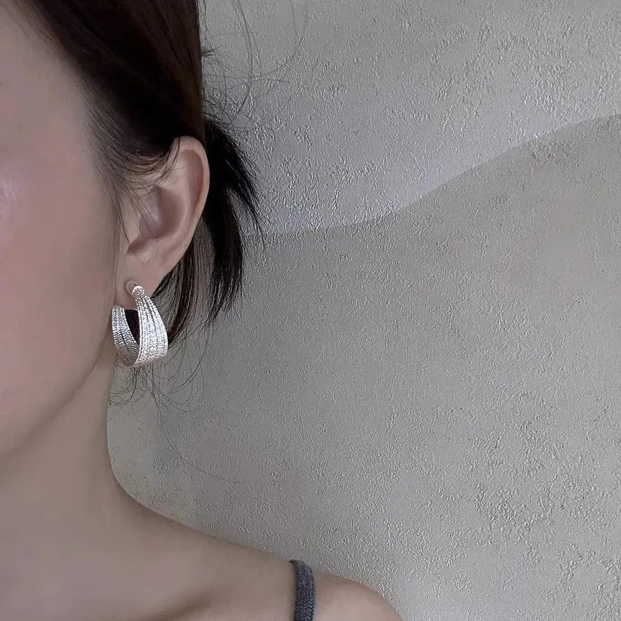 A pair of multi-layer geometric earrings in gold or silver electroplated finish, available as studs or clips.