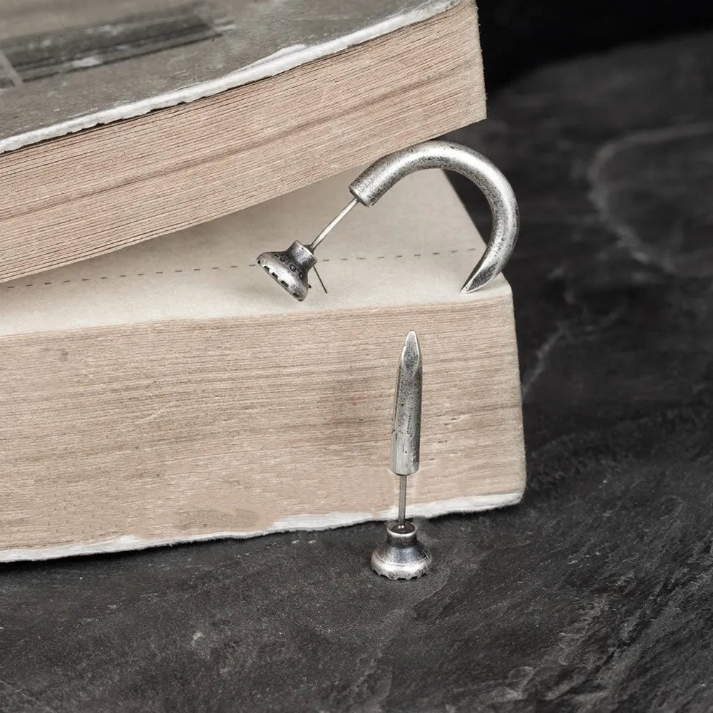 Sterling silver punk-style nail stud earrings on ear hook, showing straight and curved nail designs.