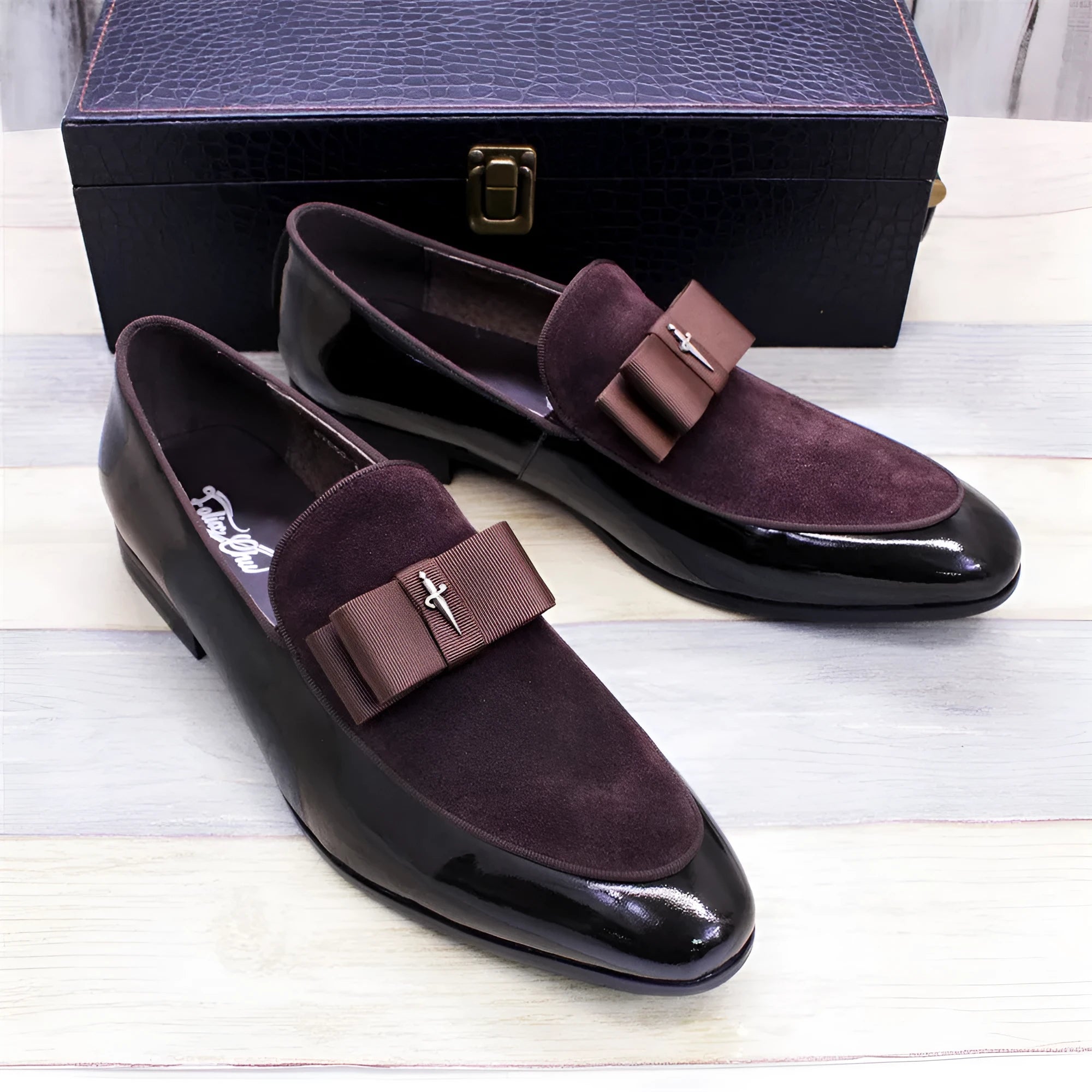 Men's black patent leather low-top shoes with a gold tassel detail on a white background.