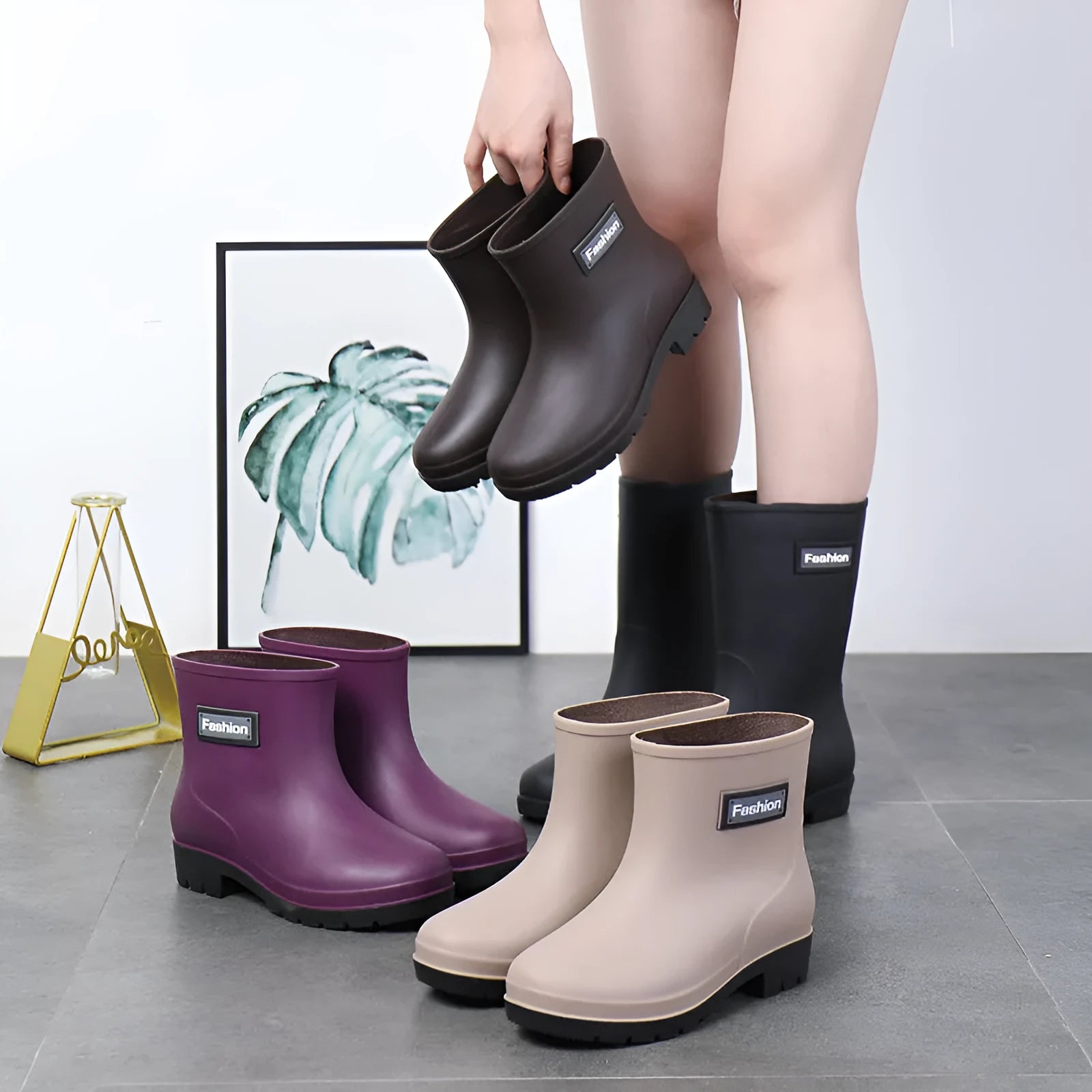 Women's black PVC mid-calf rain boots with a low heel on a wet surface.