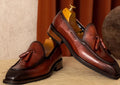 Men's black genuine leather slip-on loafers with fringed detailing and a rubber sole, shown from a side view.