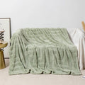 Thick square coral fleece flannel blanket in brown colour shown folded on a sofa