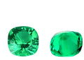 Selection of polished cultivated emerald gemstones in Columbia green colour on a white background, showing various shapes and sizes.