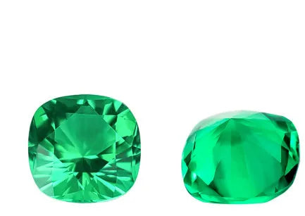 Selection of polished cultivated emerald gemstones in Columbia green colour on a white background, showing various shapes and sizes.