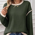 Beige loose knit top with green four leaf clover contrast trim and drop shoulders.