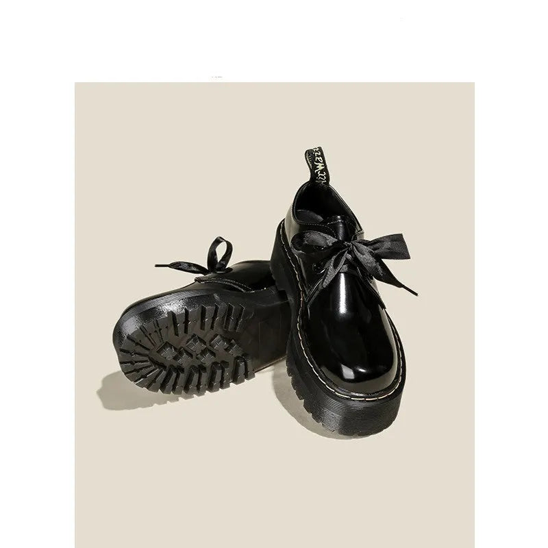 Women's black thick-soled leather-style lace-up shoes with ribbon and cross strap details on a white background.