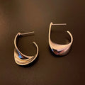 Gold and silver twisted geometric metal earrings with a round design element.