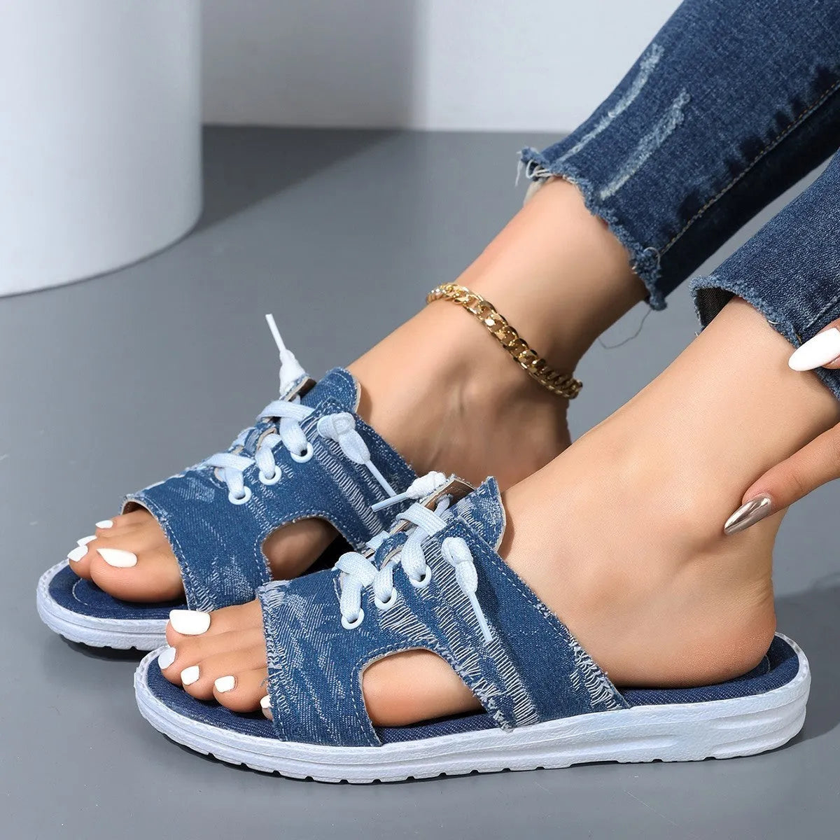 Blue women's Roman-style flat canvas slippers with a rubber sole, shown from the side.