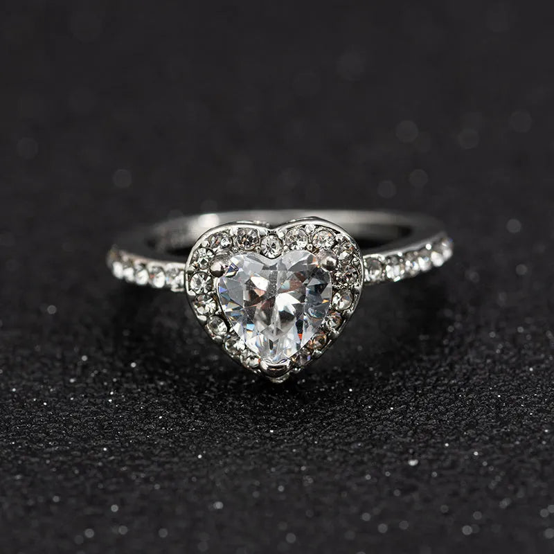 Heart-shaped crystal wedding ring in rose gold or silvery finish on white background