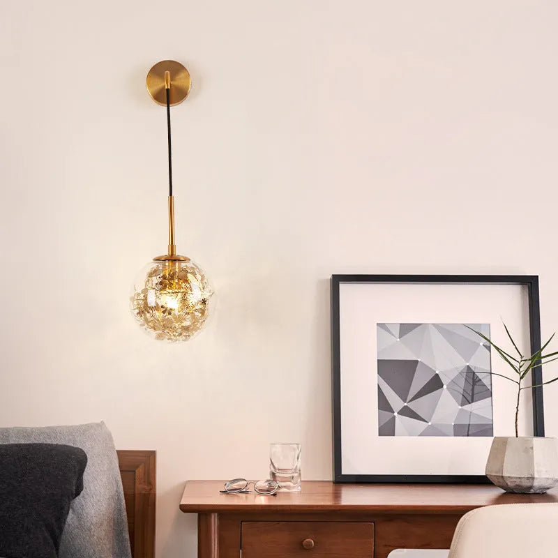 Modern glass wall lamp in golden flower finish mounted beside bed