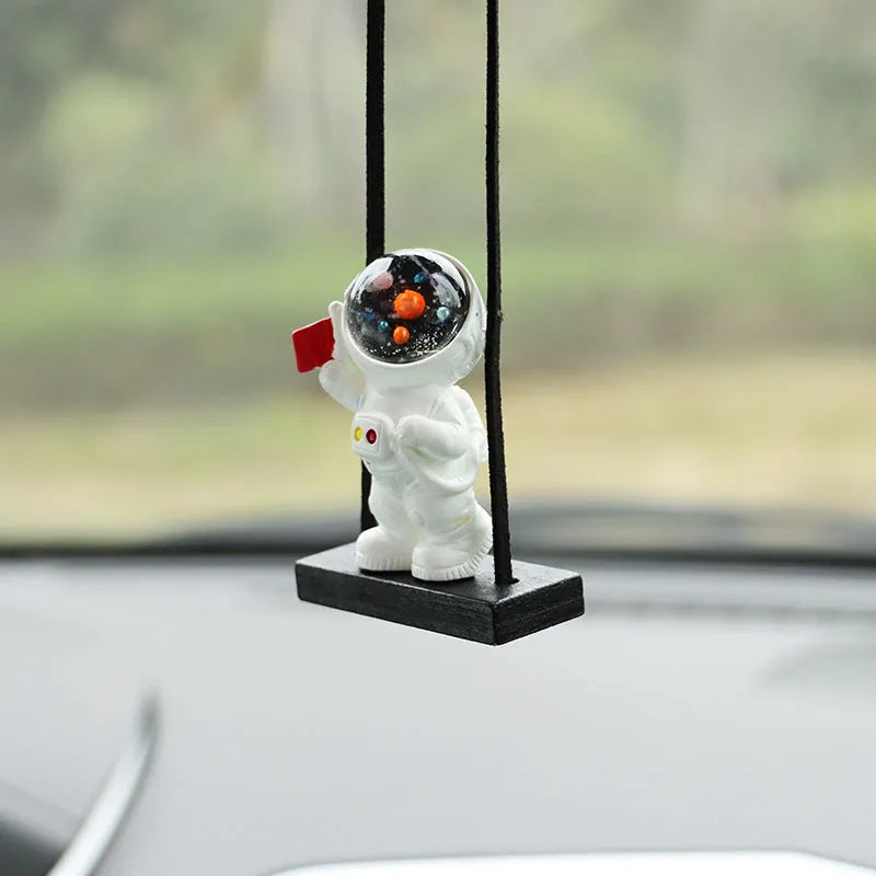 Colourful resin astronaut cartoon character car pendant hanging from a sun visor.