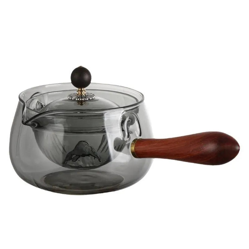 Semi-automatic rotary heat-resistant glass teapot with infuser and wooden handle on a table, transparent or grey