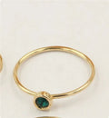Gilded copper knuckle ring with a blue cubic zirconia stone on a model's hand.