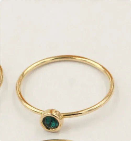 Gilded copper knuckle ring with a blue cubic zirconia stone on a model's hand.