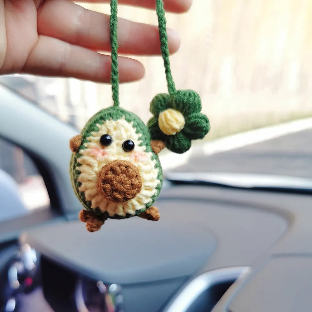 Handmade crocheted car pendant in avocado, pink rainbow, and red rainbow cartoon designs.