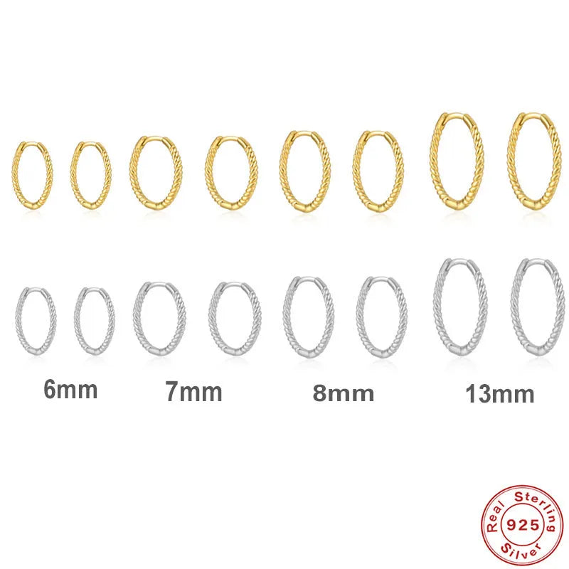 Twisted round sterling silver hoop earrings in golden and white gold colours on a plain background.