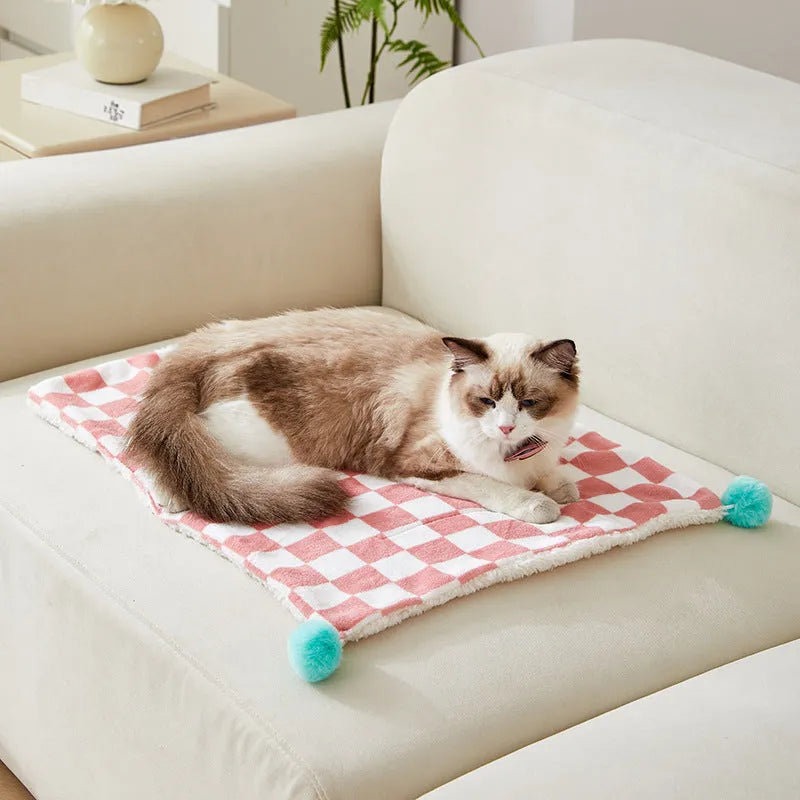 Green plush pet blanket with plaid pattern and fur balls as dog bed mat on sofa