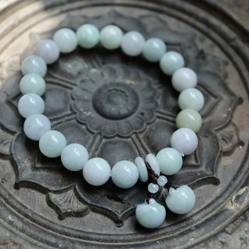 Apple green jade bracelet with carved Maitreya Buddha, gourd, and money bag beads.