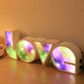 Rainbow-coloured plastic LED light spelling LOVE, standing 35.5cm tall on a table.